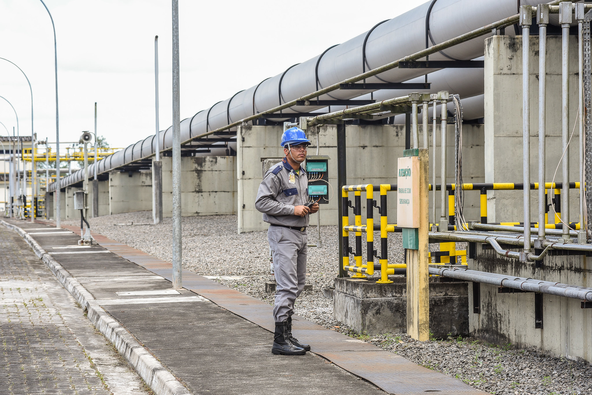 Petrobras anuncia venda de UPGN e 28 campos na Bahia. Na imagem: Rede de dutos e trabalhador branco, uniformizado e com capacete de segurança em área de produção terrestre de petróleo no Poço Candeias, na Bahia (Foto: Saulo Cruz/MME)