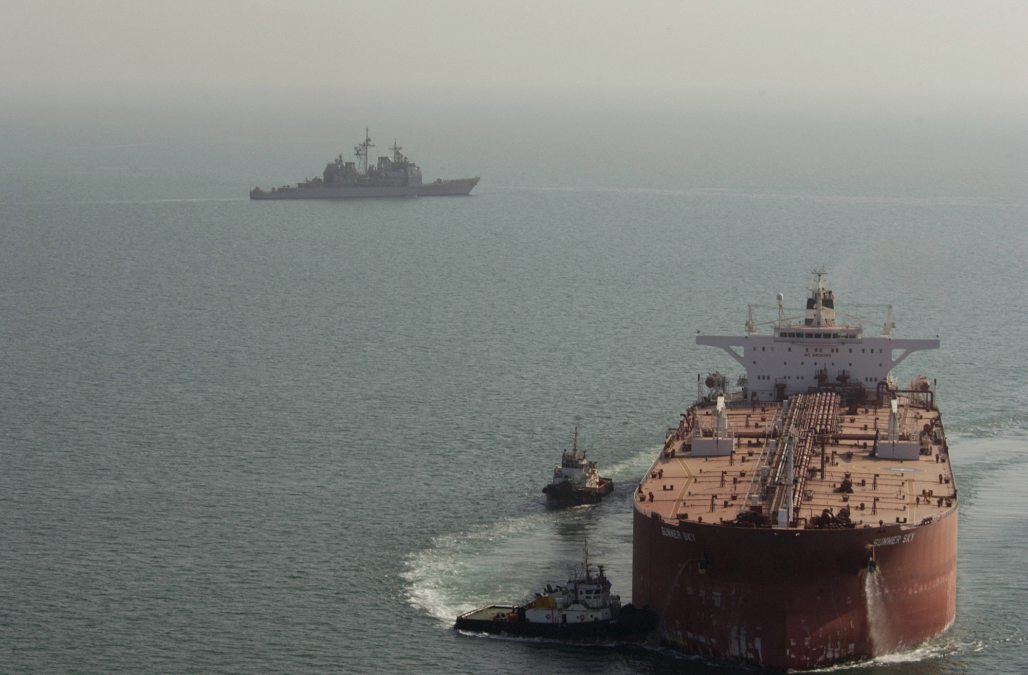 041028-N-1348L-128
The guided missile cruiser USS Mobile Bay (CG 53) (left) patrols the waters surrounding the Al Basrah oil terminal as two Iraqi tug boats guide a super oil tanker into place on Oct. 28, 2004.  The tanker will remain in port for the next several days taking on crude oil.  The Mobile Bay is among several U.S. Navy, U.S. Coast Guard and coalition ships that share the responsibility of patrolling and safeguarding Khawr Al Amaya and Al Basrah oil terminals.  DoD photo by Petty Officer 1st class David C. Lloyd, U.S. Navy.   (Released)