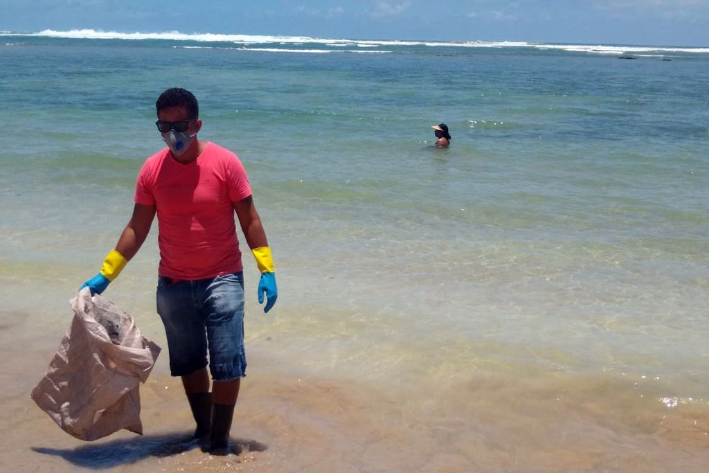 O voluntário Robério Nunes ajuda no trabalho de retirada de óleo de praia em Morro de São Paulo, na Bahia