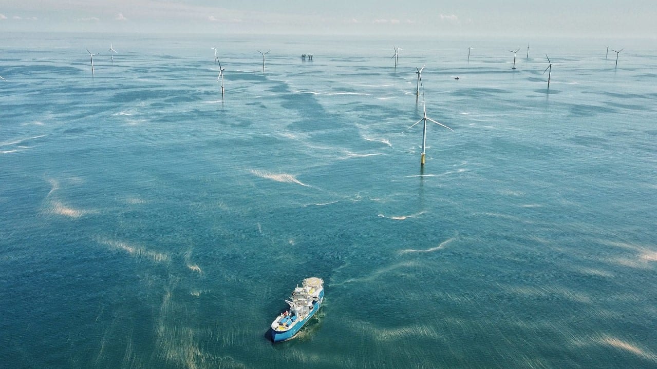 IEA: investimento em energia volta a crescer em 2021, mas distante de rota de neutralidade de carbono. Na imagem: Embarcação próxima a turbinas eólicas offshore, em mar azul com pequenas ondas pelo vento (Foto: GWEC)