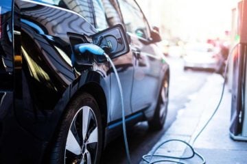 Carros elétricos têm recorde de vendas no Brasil em 2021. Na imagem: Carro elétrico preto conectado a ponto de recarga (Foto: Freepik)