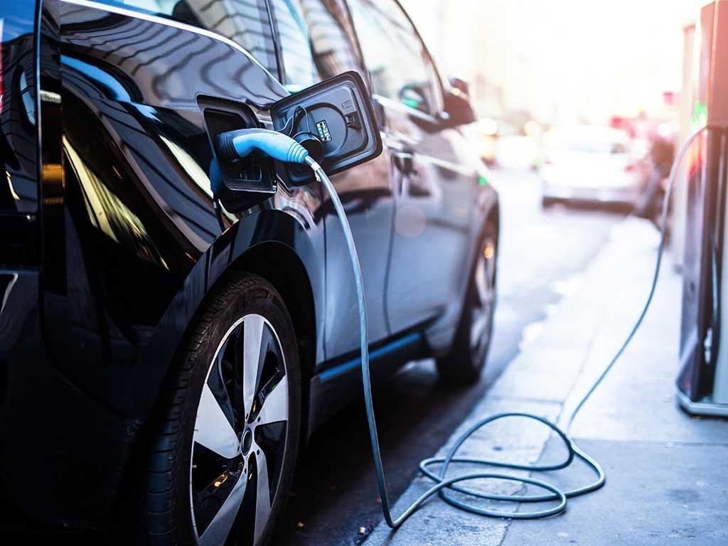 Venda de veículos elétricos e híbridos aumenta 91% no Brasil e bate recorde em 2023, conheça o ranking. Na imagem: Carro elétrico preto conectado a ponto de recarga (Foto: Freepik)