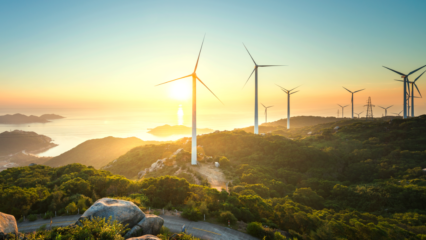 Sol, a fonte energética de (quase) todas as formas de energias. Na imagem: Turbinas eólicas sobre montanhas cobertas com vegetação e, ao fundo, sol brilhando se reflete no oceano (Foto: Reprodução X EY)