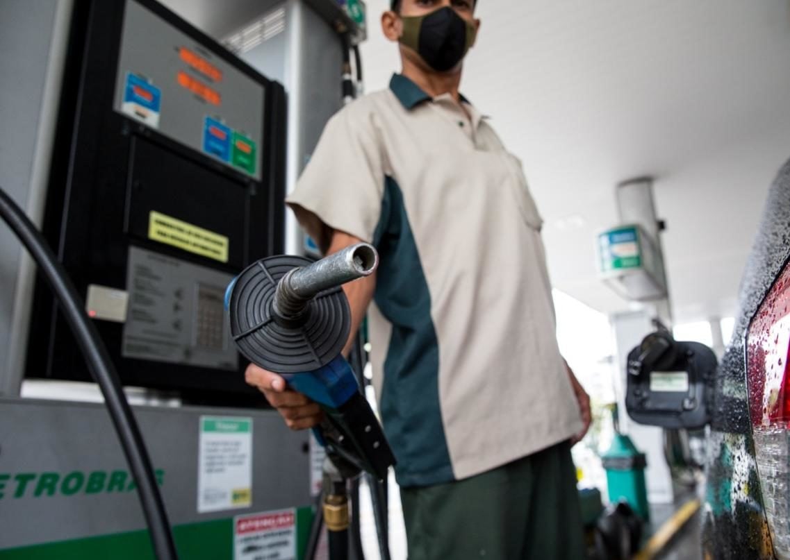 Preço da gasolina segue defasado, diz Ativa Investimentos. Na imagem: Frentista segura bomba de abastecimento em posto de combustíveis, apontando o bico para a câmera; ao lado, um veículo preto (Foto: Divulgação Petrobras)