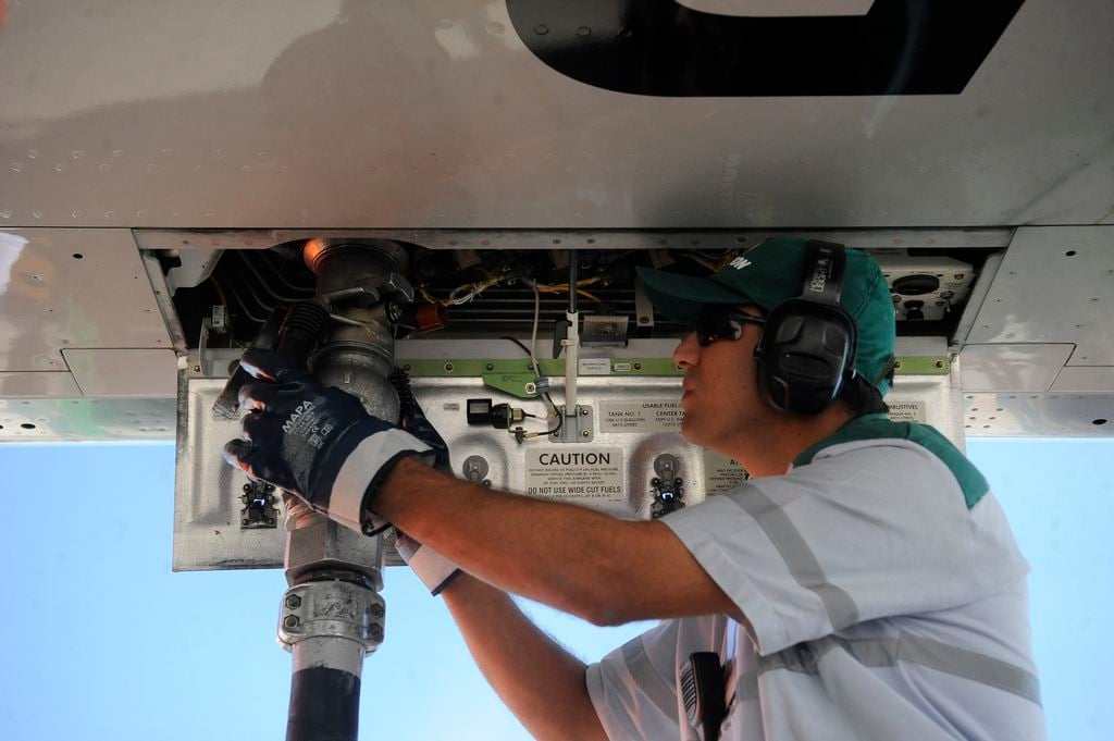 Combustível do Futuro define proposta para descarbonizar a aviação. Na imagem: Homem branco conecta, à parte de baixo de aeronave, mangueira para abastecimento de aeronave com SAF, biocombustível de aviação (Foto: Tânia Rêgo/Agência Brasil)