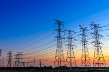 O potencial da substituição de instalações de transmissão de energia. Na imagem: Foto à contraluz de grandes torres com linhas de transmissão de energia ,sob céu azul com pôr do sol ao fundo (Foto: iStock)