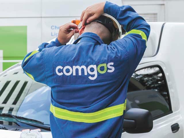 Comgás busca gás natural, para repor contratos com Petrobras que vencem este ano. Na imagem: Trabalhador da Comgás com uniforme azul, com faixas de proteção amarelas fluorescente, e capacete de proteção, coloca protetor auricular (Foto: Divulgação)