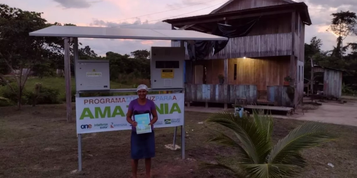 Na imagem: Mulher segura conta de luz e sorri. Programa Mais Luz Para a Amazônia leva energia elétrica a comunidades em áreas remotas (Foto: Divulgação/Energisa)