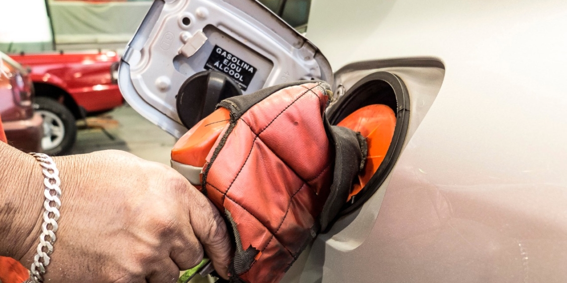 Mão de frentista branco segura bomba na cor vermelha durante abastecimento de carro flex, gasolina ou álcool (Foto Rafael Neddermeyer/Fotos Públicas)