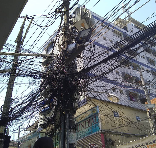 Setor elétrico está sendo derrotado pelo furto de energia, diz ex-diretor da Aneel. Na imagem: Poste de luz com emaranhado de fios de alta tensão. Gato na rede elétrica da Light, na Rocinha, Rio de Janeiro (Foto: André Ramalho)