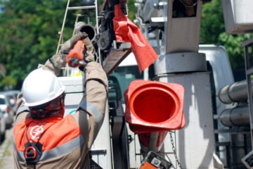 A Light pode perder a concessão? Entenda o que está em jogo na crise financeira da Light. Na imagem: Funcionário da Light, de uniforme laranja e equipamentos de proteção, faz manutenção na rede de distribuição de energia (Foto: Divulgação)