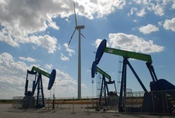 Crescimento das energias renováveis ​​não prejudicou o domínio dos combustíveis fósseis em 2022. Na imagem: Cavalos-de-pau para exploração onsore de petróleo e turbina eólica (Foto: Wiki Commons)