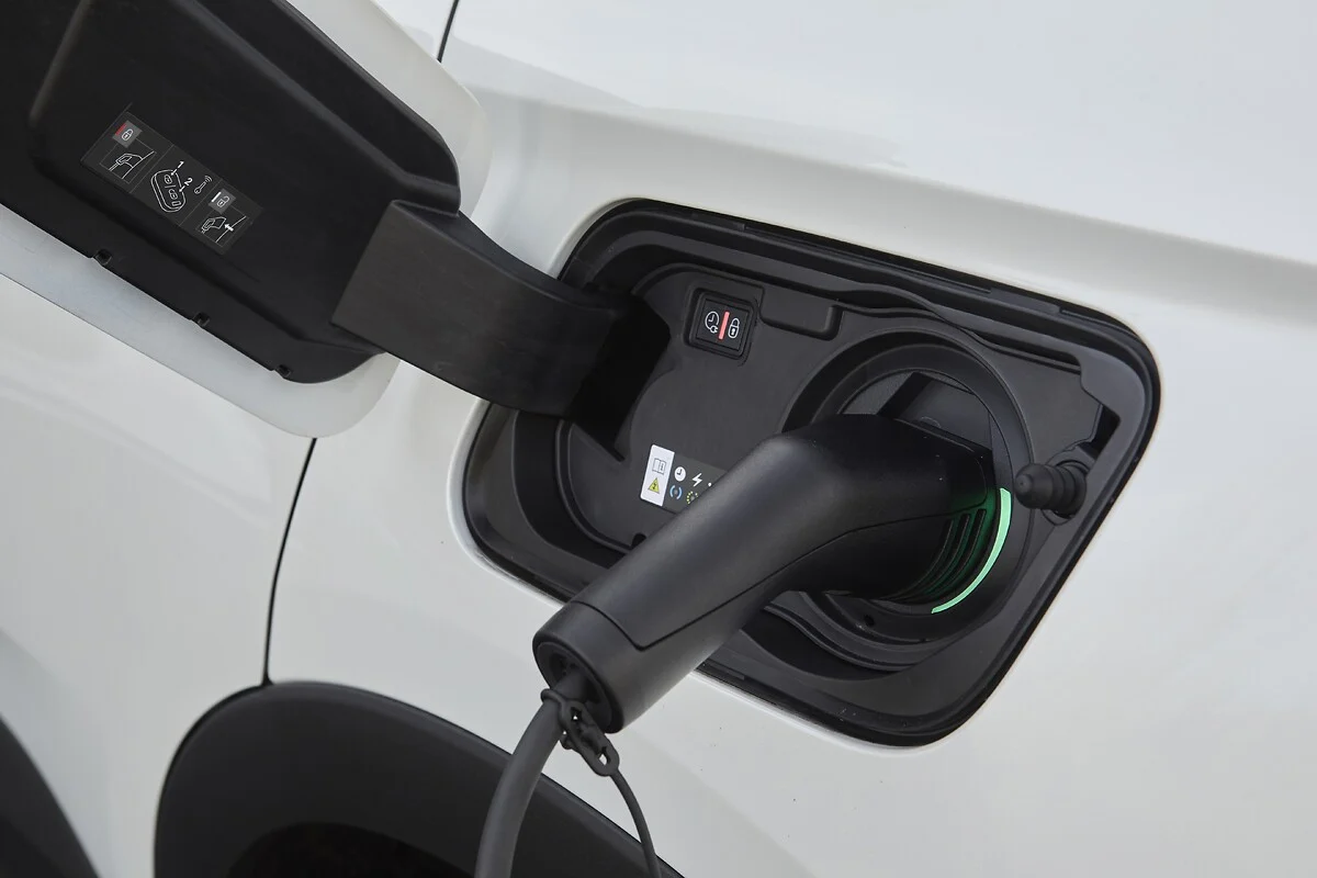 Grandes montadoras planejam rede conjunta de recarga de carros elétricos. Na imagem: Plug de recarga, preto, conectado a veículo elétrico branco