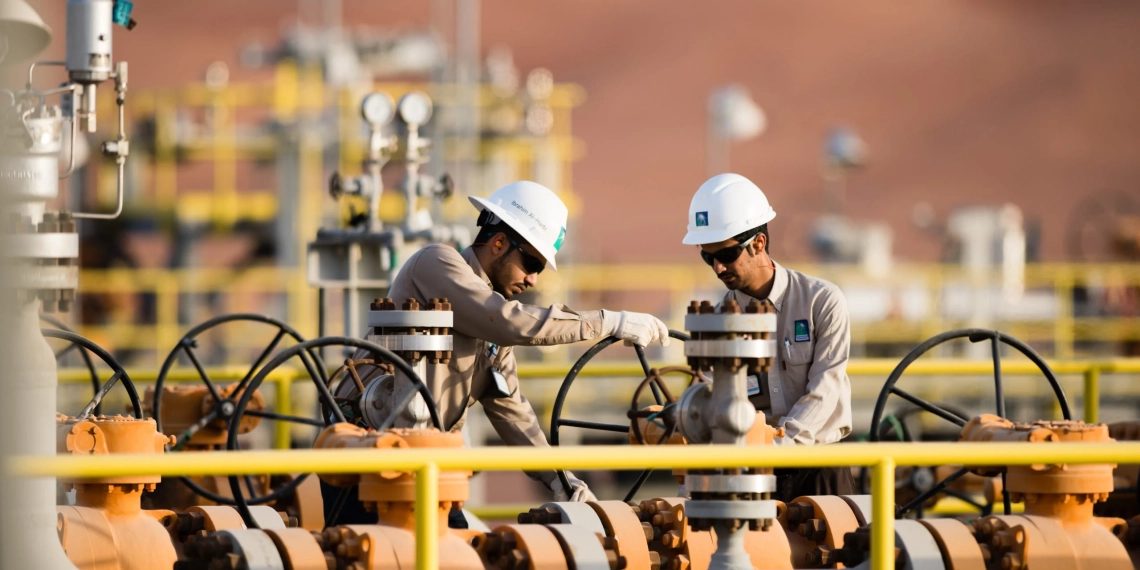 Preço do petróleo ainda resiste à pressão da Opep. Na imagem: Dois trabalhadores, com uniformes cinza e capacete de proteção branco, operam instalações em gasoduto (Foto: Divulgação/Saudi Aramco)