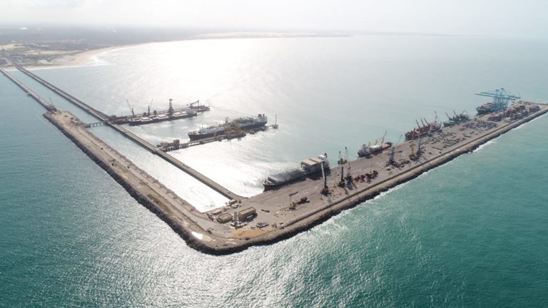 Ceará se junta a eólica, solar e biogás em pacto brasileiro do hidrogênio renovável. Na imagem: Vista aérea de embarcações no cais do porto do Pecém, com sol refletindo no mar na coloração "prateada" (Foto: Divulgação CIPP)