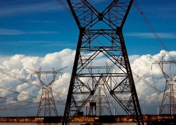 Leilão de transmissão de energia, marcado para março de 2024, prevê R$ 20,5 bilhões de investimentos. Na imagem: Central elétrica com grandes torres e linhas de transmissão de energia de alta tensão; ao fundo, densas nuvens brancas, na parte de baixo, e céu azul acima (Foto: Agência Senado)