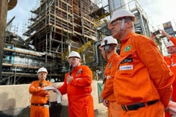 Petrobras antecipa parceria com Unigel para retorno à produção de fertilizantes. Na imagem: Jean Paul Prates discursa para trabalhadores na refinaria Refap em Canoas, no Rio Grande do Sul; todos, inclusive Prates, estão vestindo uniforme laranja e equipamentos de proteção pessoal, Jean Paul segura papéis com a mão direita e um microfone preto com a esquerda (Foto: Divulgação Petrobras)