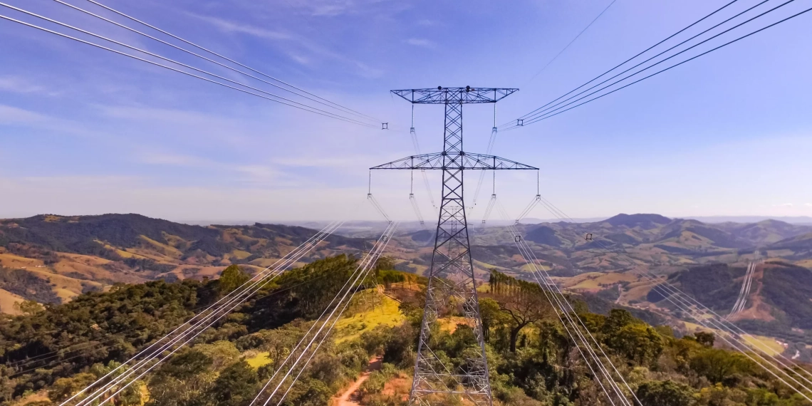 Entenda que está em jogo na criação do mercado livre de energia elétrica e principais impactos para o setor. Na imagem: Sistema de transmissão de energia Cantareira, entre MG e SP, da Elecnor do Brasil. Linhas de transmissão, em primeiro plano, e torre de grande porte, ao fundo, com céu azul (Foto: Divulgação)