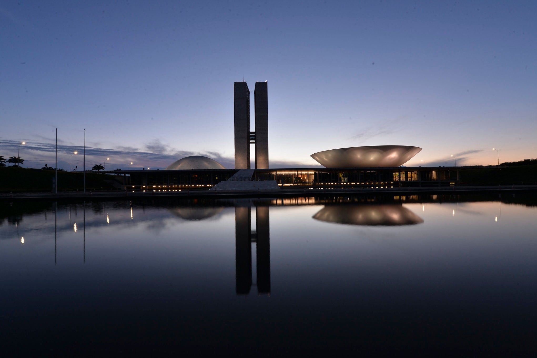 Esforço concentrado no Senado e na Câmara para aprovação do Combustível do Futuro e definições do setor de energia. Na imagem: Congresso Nacional fotografado ao anoitecer, com cúpulas e torre central, ao fundo, refletidas no espelho d'água, em primeiro plano (Foto Edilson Rodrigues/Agência Senado)