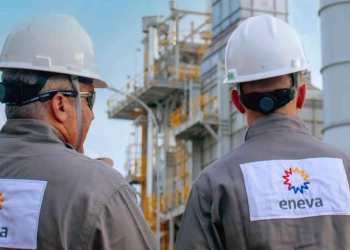 Eneva propõe fusão com a Vibra e espera acelerar a interiorização e as vendas de gás natural. Na imagem: Planta da Eneva com dois trabalhadores (homens da cor branca), fotografados de costas conversando, com uniformes cinza e capacetes de proteção brancos (Foto: Divulgação)