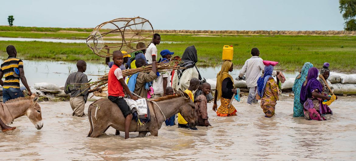 Refugiados climáticos: moradores de Rann, no nordeste da Nigéria, caminham pela estrada principal inundada, inacessível para veículos; Milhões de pessoas enfrentam a fome e as vidas de crianças estão em risco no nordeste da Nigéria, em meio a um conflito prolongado e da intensificação das alterações climáticas (Foto: Christina Powell/Ocha)