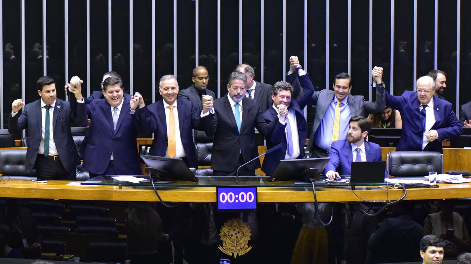 Imposto no petróleo e desoneração do hidrogênio marcam escolhas políticas na reforma tributária, que deve ser promulgada nessa quarta (20/12). Na imagem: Arthur Lira, Aguinaldo Ribeiro e outros deputados comemoram, de mãos dadas, a aprovação da PEC 45/2019, que simplifica o sistema tributário brasileiro (Foto: Zeca Ribeiro/Câmara dos Deputados)