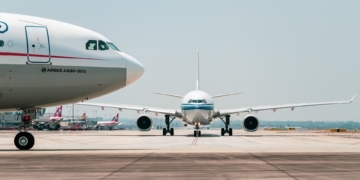 Produção de combustíveis sustentáveis de aviação (SAF) deve triplicar em 2024, mas entraves persistem, diz Iata. Na imagem: Visão lateral da parte frontal de aeronave e, ao fundo, visão frontal de outro avião, em pista de aeroporto (Foto: 穿着拖鞋一路小跑/Pixabay)