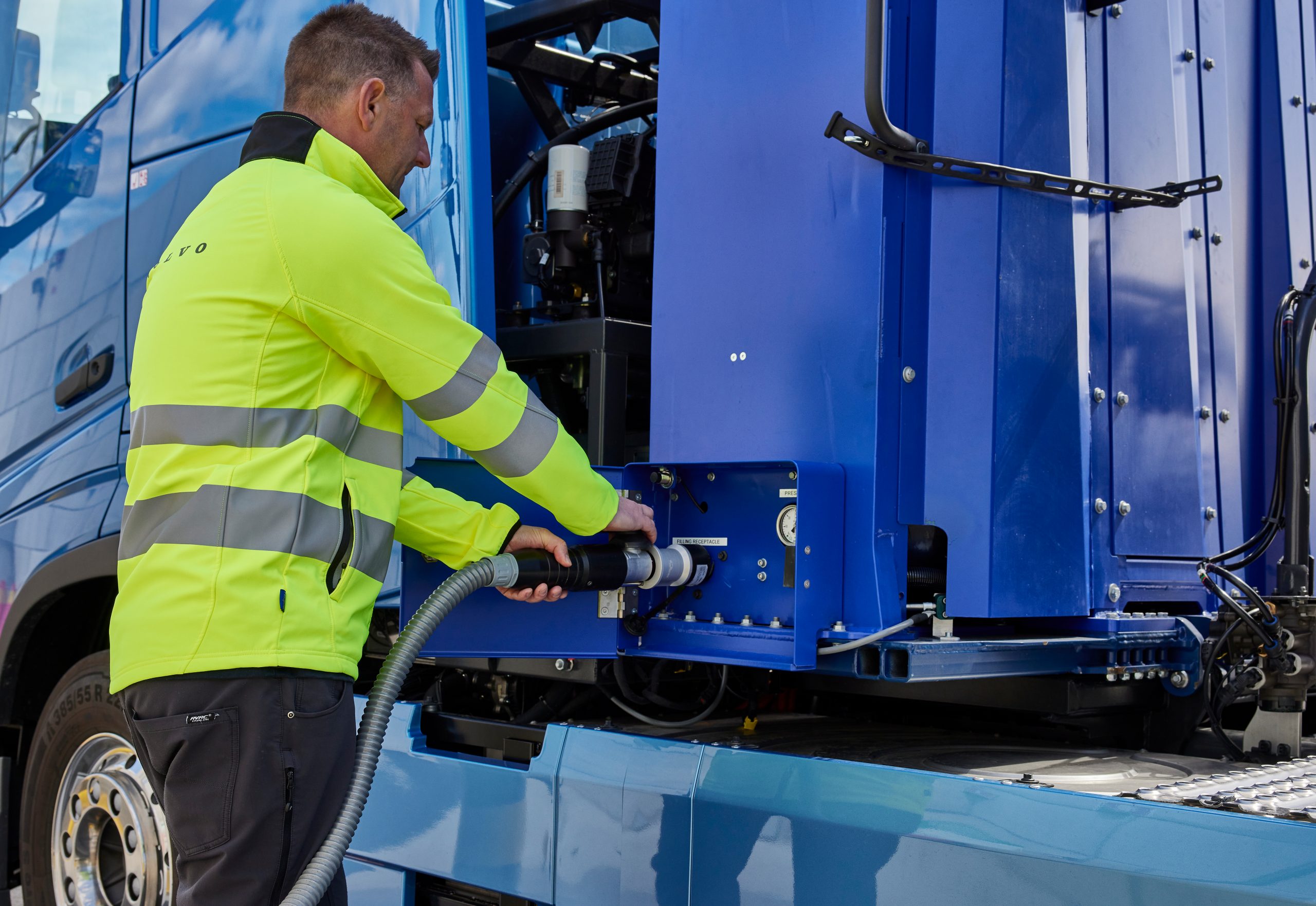 Em Davos, Alexandre Silveira (Minas e Energia) defende mandato de hidrogênio em países ricos. Na imagem: Caminhão elétrico azul da Volvo conectado a carregador elétrico por trabalhador com uniforme amarelo. Volvo apresenta na Europa e EUA caminhão com células de combustível a hidrogênio, com zero emissões (Foto: Divulgação)