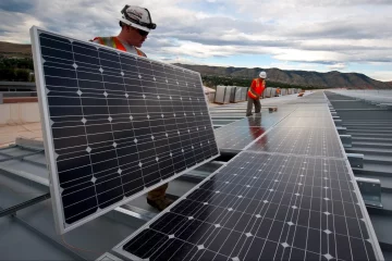 Imposto sobre painéis solares importados é "retrocesso" e afeta 85% dos projetos no Brasil, diz Absolar. Na imagem: Trabalhadores instalam painéis fotovoltaicos sobre uma longa extensão; vestem colete de proteção laranja e capacetes brancos com lanternas acopladas (Foto: Skeeze/Pixabay)