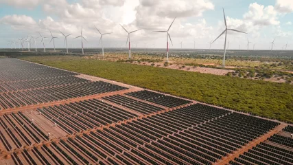 Brasil bate recorde de expansão da geração de energia elétrica no ano de 2023. Na imagem: Vista de usina híbrida eólica e solar fotovoltaica, com inúmeras fileiras de módulos fotovoltaicos, em primeiro plano, e aerogeradores, ao fundo, à direita (Foto: Divulgação Voltalia)