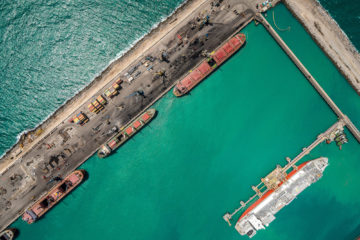 Na imagem: Vista aérea vertical de embarcações atracadas no cais do Porto do Pecém, com água esverdeada ao redor (Foto: Divulgação)