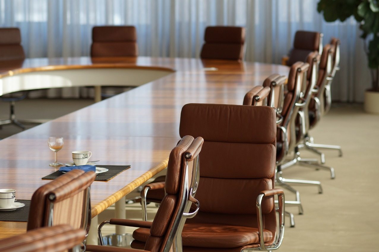 Gap de gênero no mercado global de trabalho é muito mais amplo do que se pensava, diz Banco Mundial. Na imagem: Sala de reuniões com mesa de madeira em formato circular com cadeiras estofadas em couro na cor marrom (Foto: Patrick Sommer/Pixabay)