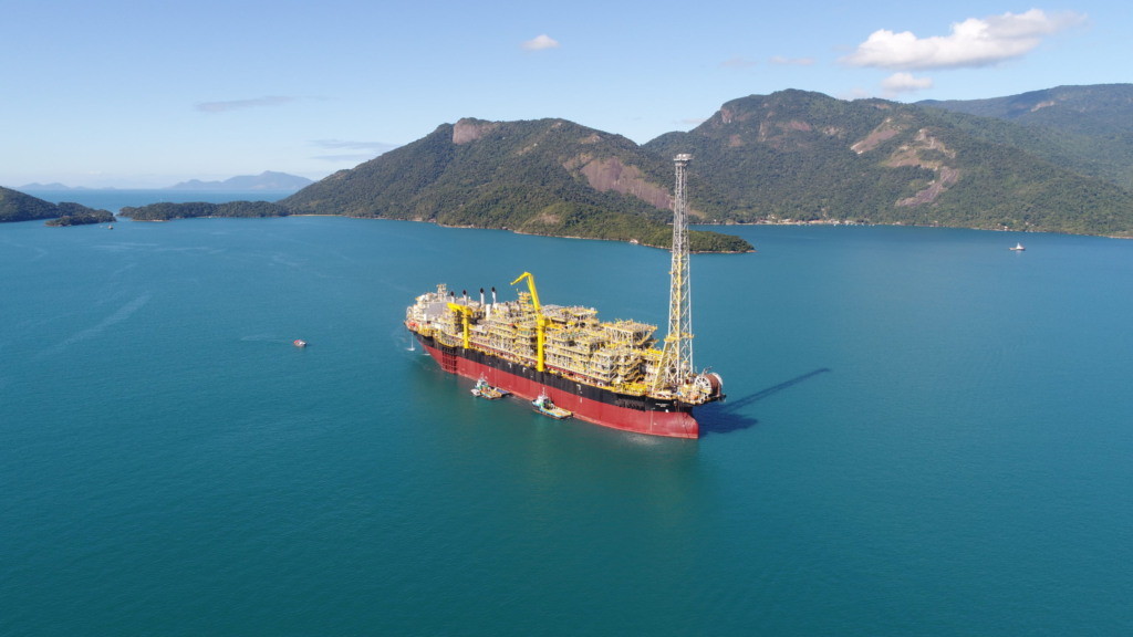 Plano Decenal de Expansão de Energia (PDE) 2034 indica queda antecipada na produção de petróleo. Na imagem: Vista de Navio-plataforma em alto mar com montanhas ao fundo. FPSO Carioca rumo ao campo de Sépia, na Bacia de Santos (Foto: Cortesia Modec)