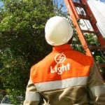 Na imagem: Técnico da Light em serviço de reparo à rede, com equipamentos de segurança, no alto de uma escada encostada em um poste de eletricidade (Foto: Paula Kossatz/Divulgação)