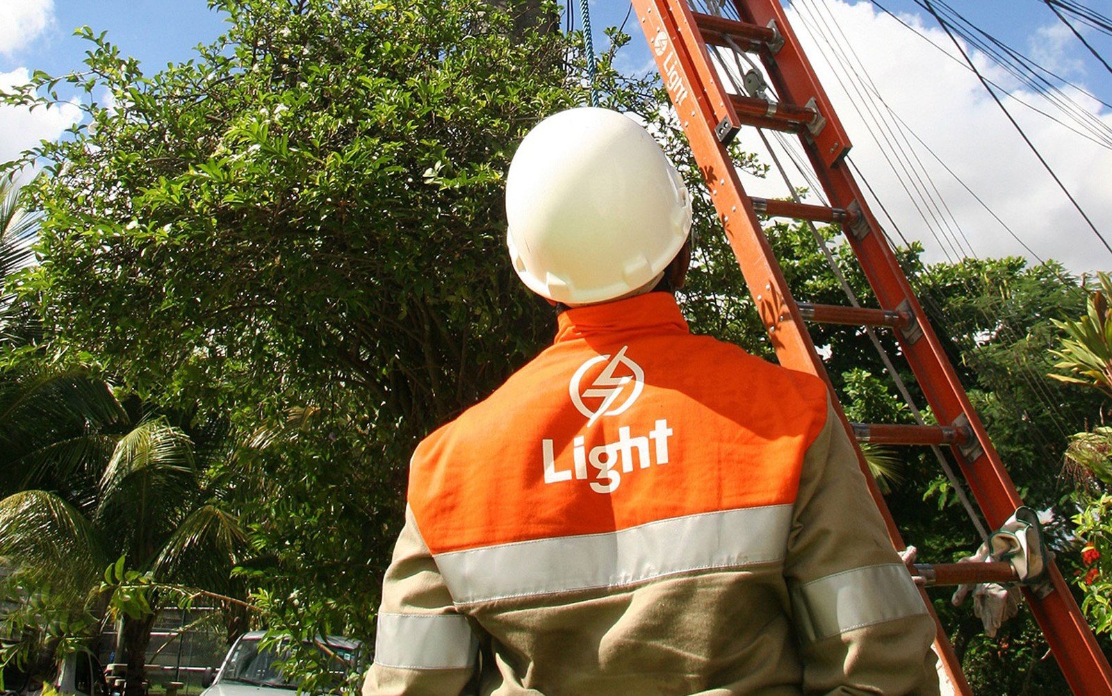 Na imagem: Técnico da Light em serviço de reparo à rede, com equipamentos de segurança, no alto de uma escada encostada em um poste de eletricidade (Foto: Paula Kossatz/Divulgação)