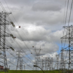 Linhas de transmissão de energia do Rio Grande do Sul serão licitadas em leilão de 2025. Na imagem: Linhas de transmissão de energia elétrica do Rio Grande do Sul deverão ser licitadas em 2025. Na imagem: Torres de transmissão de energia com cabos de alta tensão sob céu encoberto de nuvens acinzentadas (Foto: Divulgação)