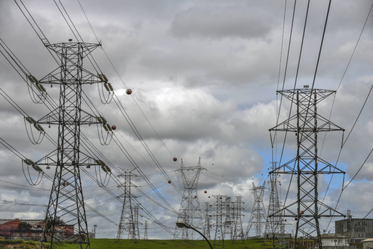 Linhas de transmissão de energia do Rio Grande do Sul serão licitadas em leilão de 2025. Na imagem: Linhas de transmissão de energia elétrica do Rio Grande do Sul deverão ser licitadas em 2025. Na imagem: Torres de transmissão de energia com cabos de alta tensão sob céu encoberto de nuvens acinzentadas (Foto: Divulgação)