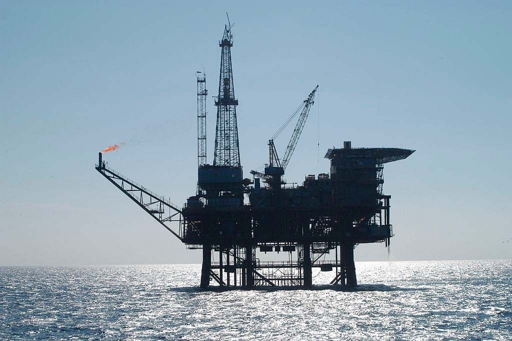 Preços brent e WTI de petróleo mantém viés de baixa mesmo com melhora no cenário macroeconômico. Na imagem: Plataforma para exploração offshore de óleo e gás com sol refletindo no mar "prateado" (Foto Wiki Commons)