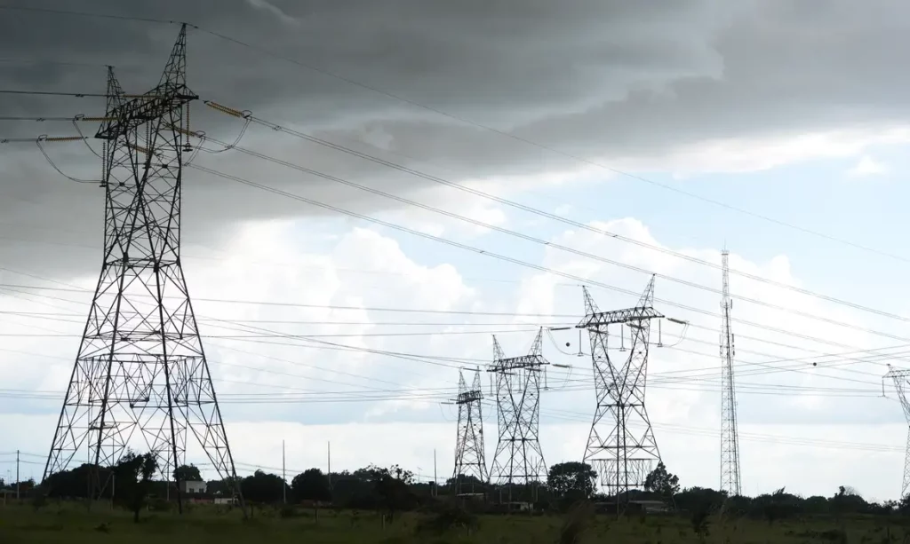 Aneel muda bandeira tarifária vermelha de setembro para o patamar 1, após correção de dados do ONS. Na imagem: Torres de transmissão de energia elétrica de alta tensão com céu nublado ao fundo (Foto Fábio Rodrigues Pozzebom/Agência Brasil)