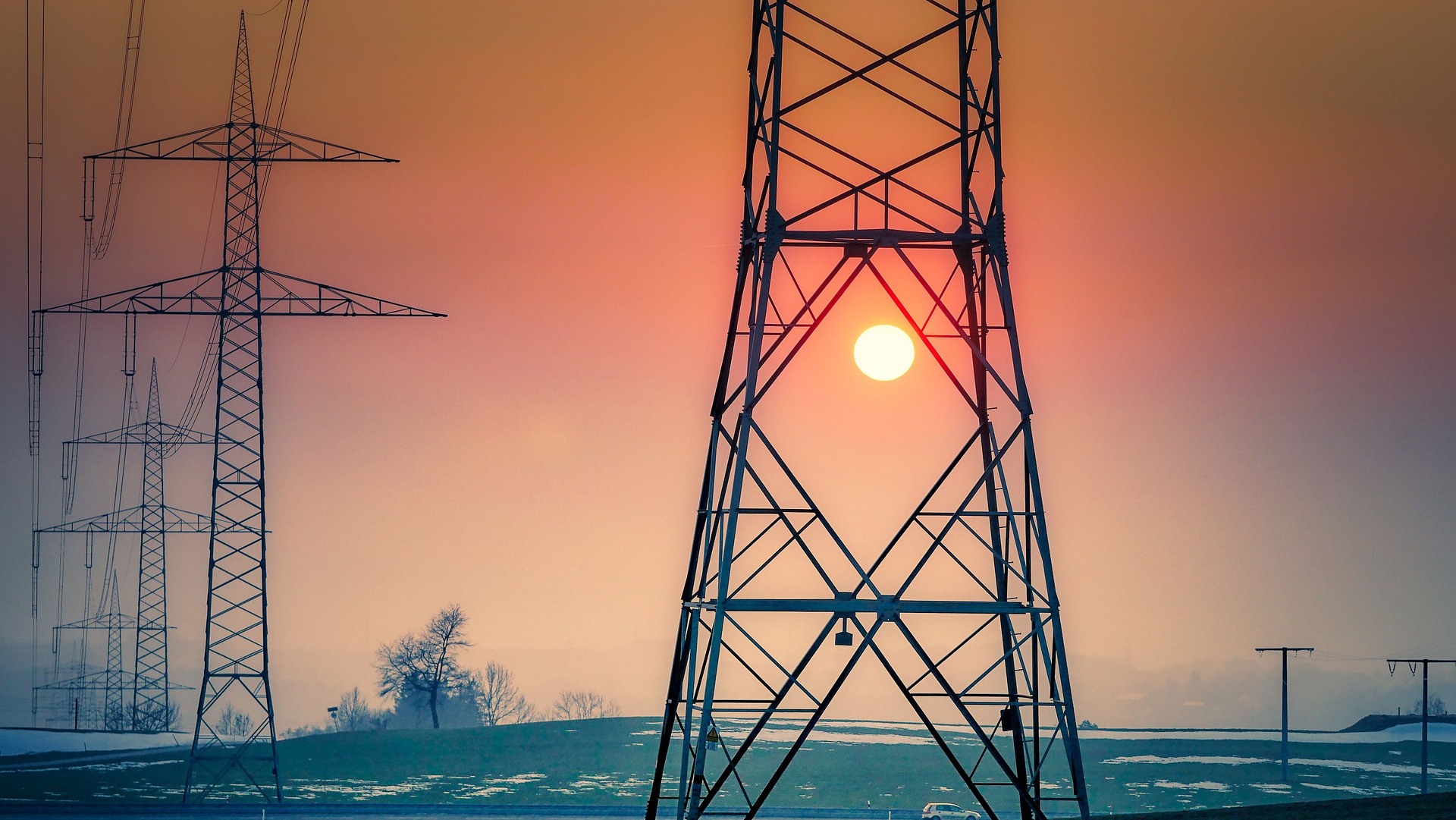 Na imagem: Torres de transmissão de energia elétrica de alta tensão com sol se pondo ao fundo (Foto Albrecht Fietz/fietzfotos/Pixabay)