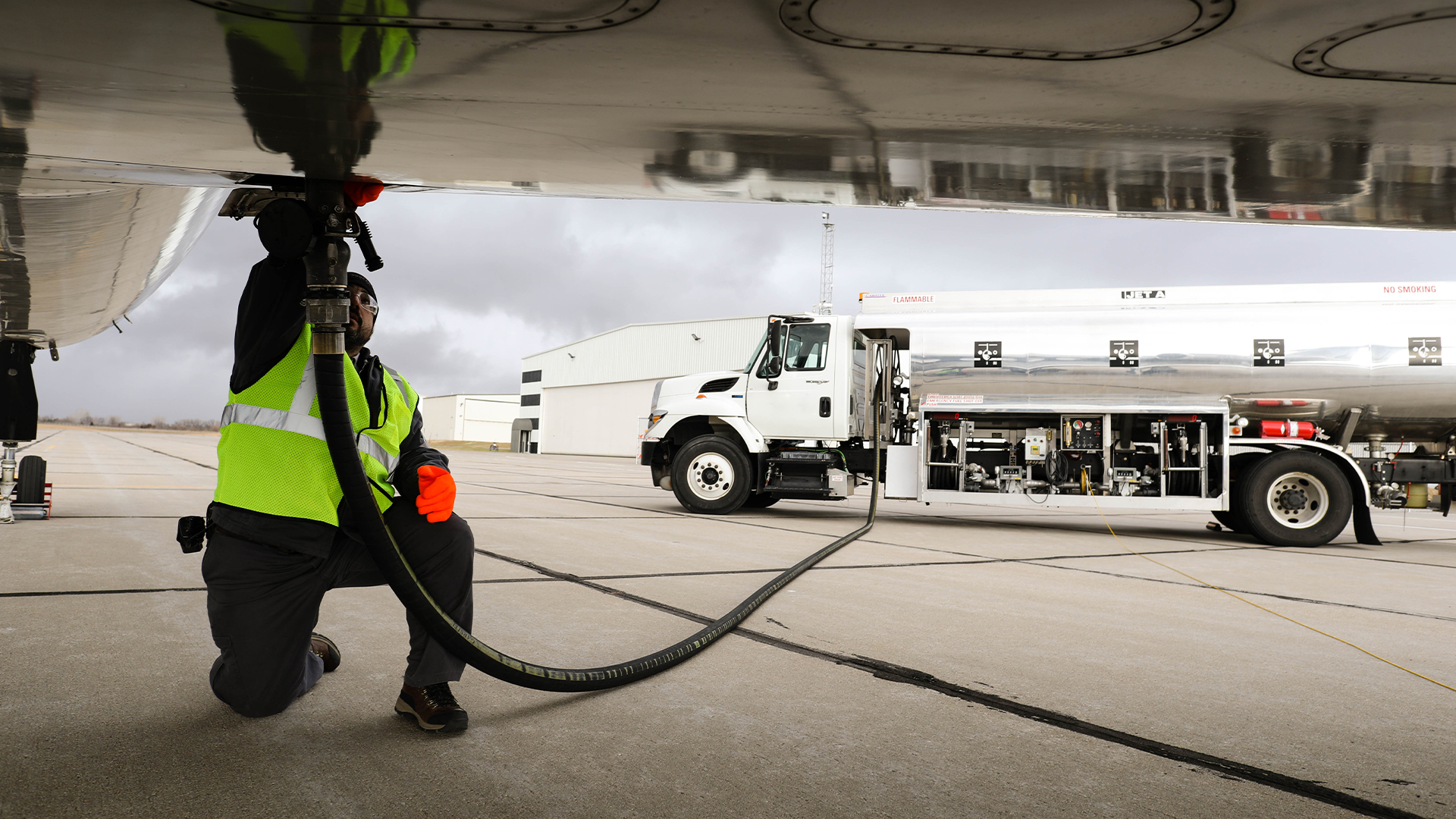 Brookfield investe US$ 1 bilhão na produção de SAF, além de e-SAF. Na imagem: Trabalhador conecta mangueira de caminhão tanque à compartimento na parte de baixo da asa de aeronave para abastecimento (Foto EiDA)