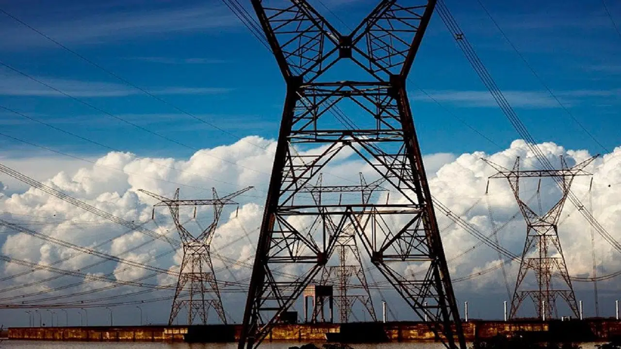 Central elétrica com grandes torres e linhas de transmissão de energia de alta tensão; ao fundo, densas nuvens brancas, na parte de baixo, e céu azul acima (Foto Agência Senado)