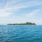 Na imagem: Vista de ondulações do mar azul e, ao fundo, ilha coberta com vegetação (Foto Pexels/Pixabay)