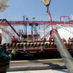 Trabalhadores conectam mangueiras à navio da Transpetro para abastecimento com bunker com conteúdo renovável, durante teste da Petrobras (Foto Agência Petrobras)