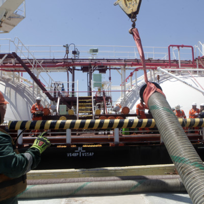 Trabalhadores conectam mangueiras à navio da Transpetro para abastecimento com bunker com conteúdo renovável, durante teste da Petrobras (Foto Agência Petrobras)