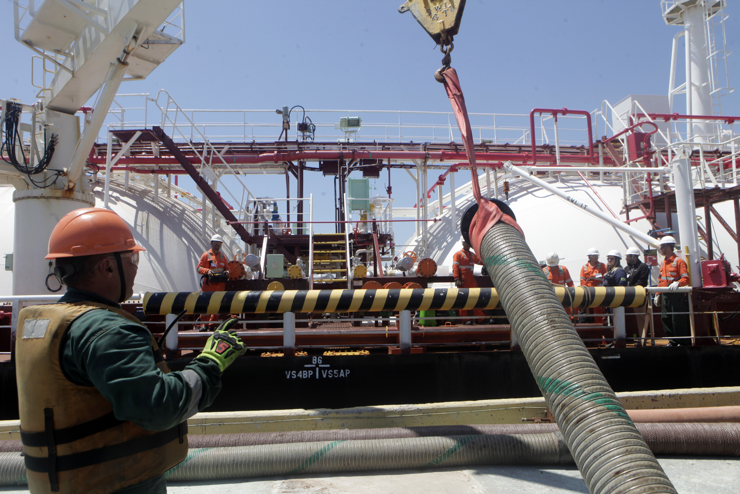 Trabalhadores conectam mangueiras à navio da Transpetro para abastecimento com bunker com conteúdo renovável, durante teste da Petrobras (Foto Agência Petrobras)