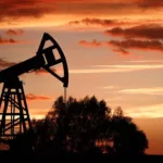Cavalos-de-pau (bombas pumpjacks) para produção de petróleo onshore na Rússia e, ao fundo, céu alaranjado (Foto Yegor Aleyev/TASS)