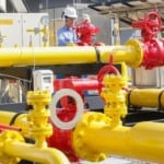 Citygate (ponto de entrega de gás) da Compagas, distribuidora de gás natural do Paraná; Rede de gasodutos nas cores amarela e vermelha, com trabalhador realizando inspeção; veste uniforme azul e capacete branco (Foto Divulgação)