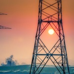 Torres de transmissão de energia elétrica de alta tensão com sol se pondo ao fundo (Foto Albrecht Fietz/Pixabay)