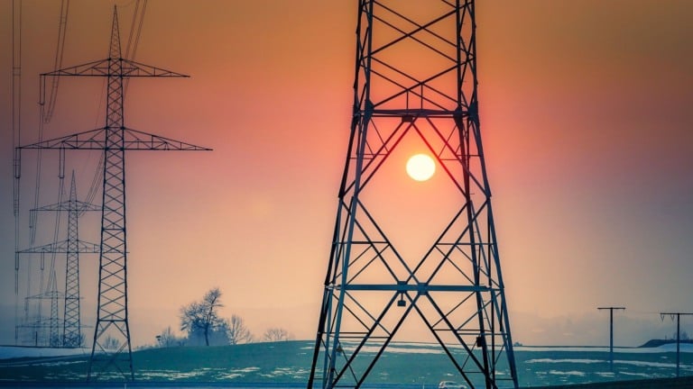 Torres de transmissão de energia elétrica de alta tensão com sol se pondo ao fundo (Foto Albrecht Fietz/Pixabay)